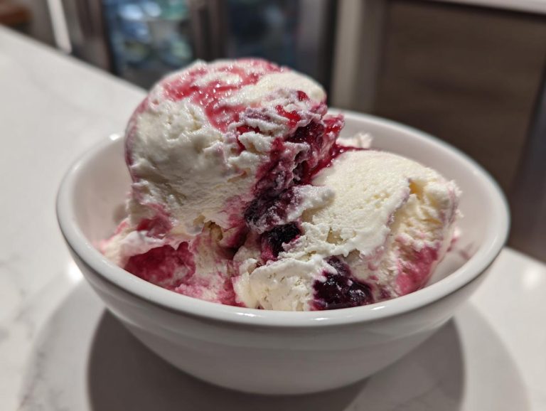 A bowl of creamy cottage cheese ice cream with a vibrant berry swirl topping.