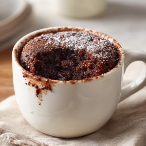 A warm Cottage Cheese Microwave Brownie in a white mug, topped with powdered sugar.