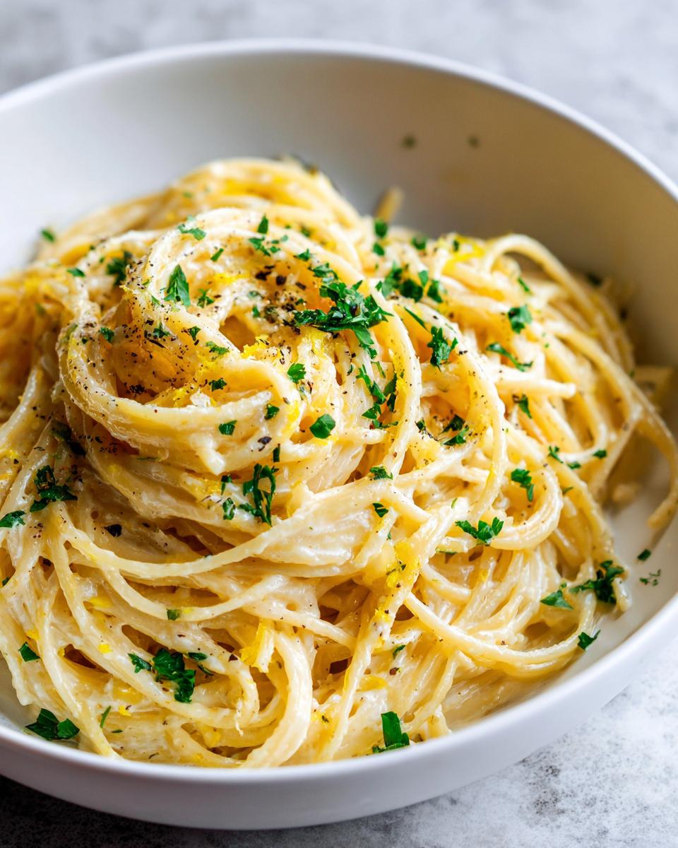 A bowl of Creamy Lemon Pasta, topped with fresh parsley and lemon zest, ready to eat.