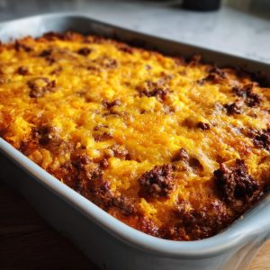 Baked Dorito Casserole in a blue baking dish, topped with melted cheese and ground beef.