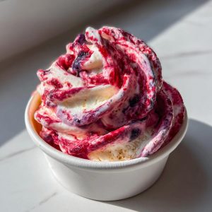 A cup of fruit roll-up ice cream with a swirl of red and purple fruit puree.