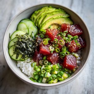 A vibrant Tuna Poke Bowl filled with tuna, avocado, cucumber, seaweed, rice, and green onions.