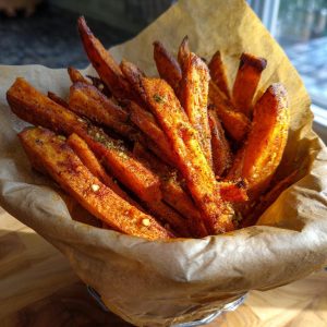 Close-up of a basket of crispy air fryer sweet potato fries seasoned with spices.