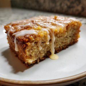 A close-up of a chewy brown butter apple blondie, drizzled with a creamy white glaze.