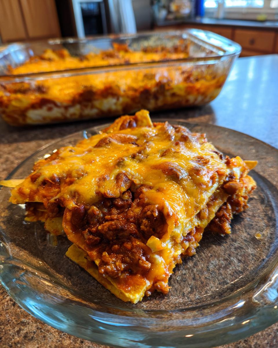 A close-up of a hearty slice of enchilada casserole, layered with tortillas, seasoned meat, and melted cheese.