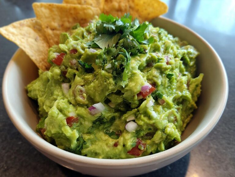 A bowl of fresh, chunky guacamole topped with cilantro and served with tortilla chips.