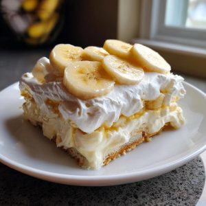 A delicious slice of Grandma's Banana Pudding topped with whipped cream and fresh banana slices.
