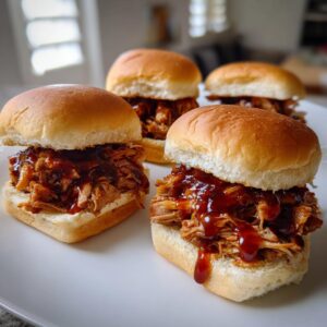 Four mouth-watering pulled pork sliders piled high with tender shredded pork and barbecue sauce on soft buns.