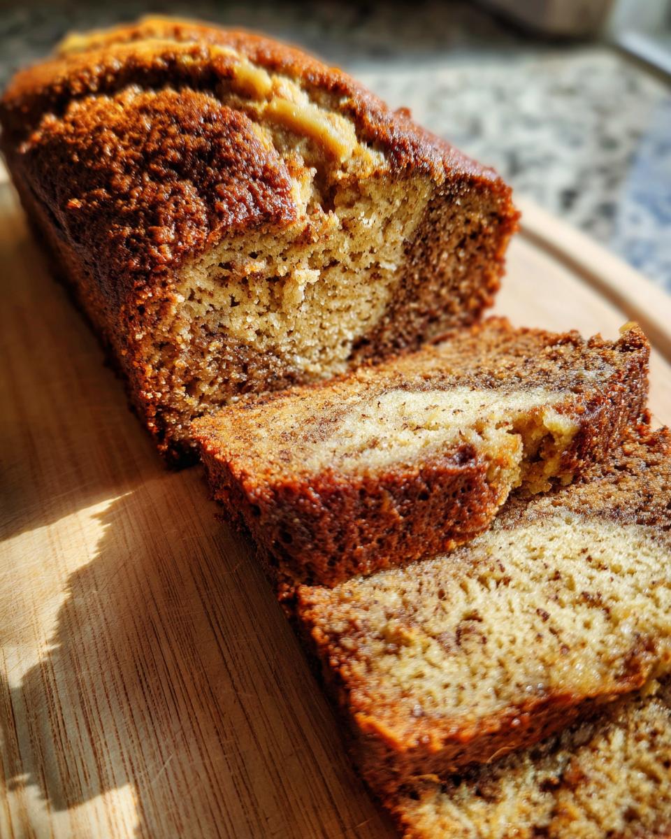 Close-up of moist pumpkin cream cheese bread, sliced on a wooden board, showing a marbled interior.