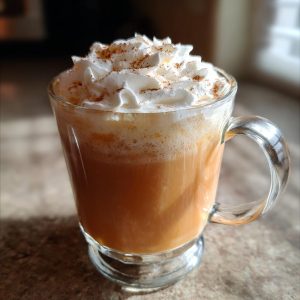 A close-up of a creamy pumpkin spice latte topped with whipped cream and cinnamon.