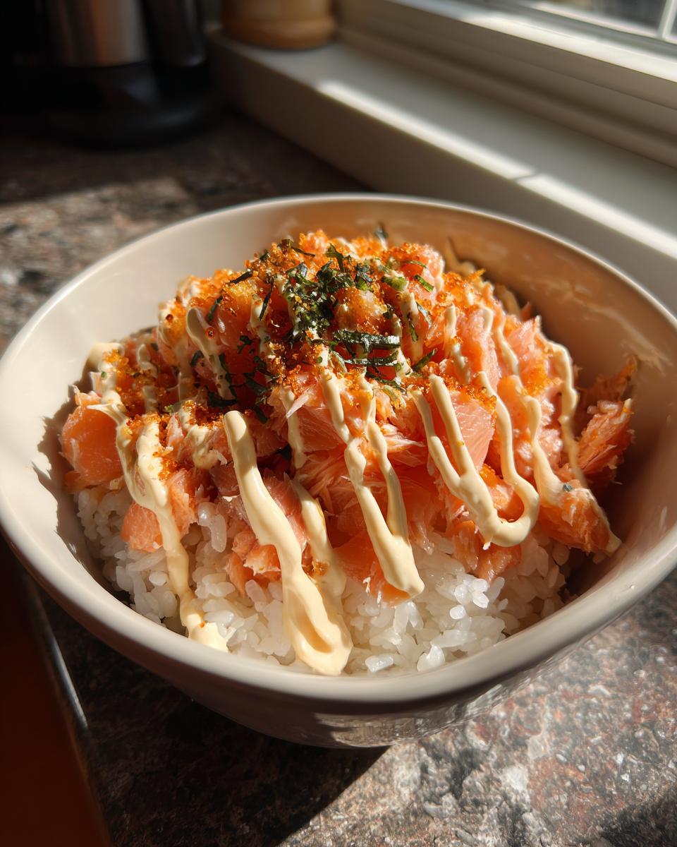 Close-up of a viral salmon rice bowl topped with flaked salmon, creamy mayonnaise, and furikake seasoning.