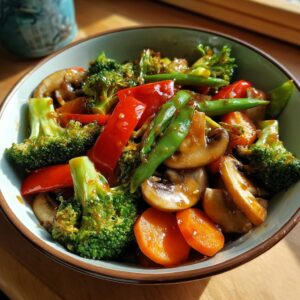A close-up of a vibrant vegetable stir fry featuring broccoli, red bell peppers, mushrooms, carrots, and green beans in a glossy sauce.