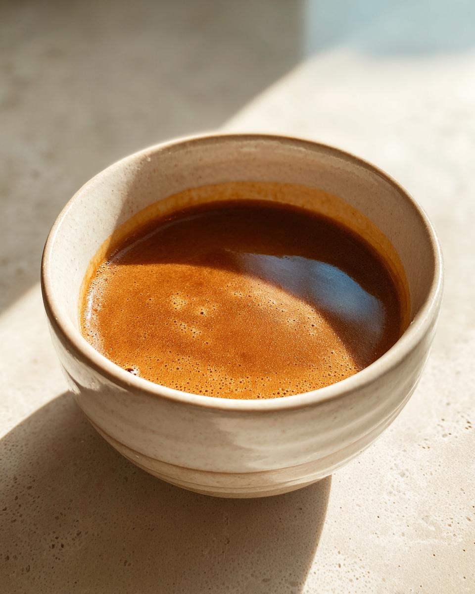 Close-up of a rich, frothy espresso in a rustic bowl, perfect for a delicious gravy.