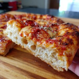A close-up of a slice of delicious homemade pizza, showing melted cheese, tomato sauce, and pepperoni on a crusty base.